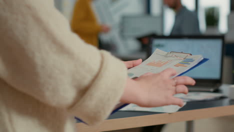 Closeup-of-woman-hands-holding-clipboard-with-papers-looking-at-pie-chart-and-business-profit-data