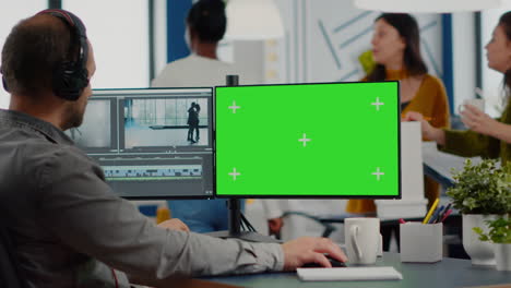 Man-videographer-with-headset-working-at-greenscreen-computer