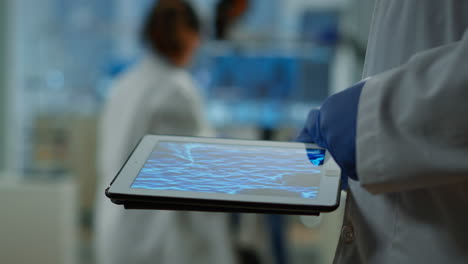 Close-up-of-researcher-using-tablet,-pointing,-analysing-DNA-informations