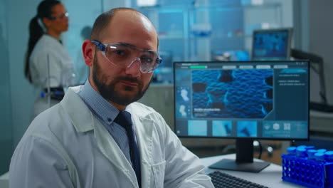 Overworked-scientist-with-protection-glasses-looking-at-camera-sighing