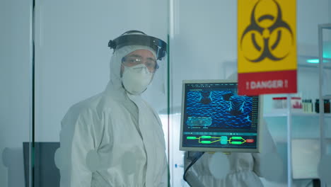 Doctor-in-ppe-suit-against-covid-19-looking-at-camera-behind-the-glass-wall