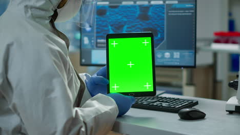 Chemist-man-wearing-protection-suit-holding-tablet-with-green-mockup