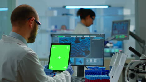Man-doctor-holding-tablet-with-green-screen-in-modern-equipped-lab