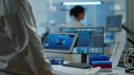 Close-up-of-scientist-in-lab-coat-working-holding-tablet