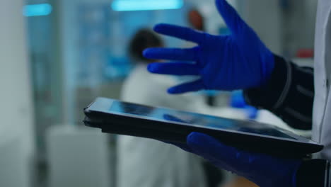 Close-up-of-scientist-examining-datas-from-tablet