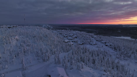 Drone-shot-circling-a-cottage-village-on-top-of-Iso-Syote,-sunset-in-Finland