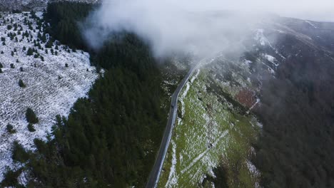 Reise-Durch-Wicklow:-Luftaufnahme-Eines-Schwarzen-Autos,-Das-Inmitten-Nebliger-Berge-Und-Schneebedeckter-Wälder-In-Die-Wolken-Fährt