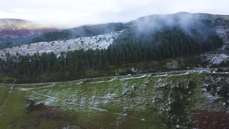 Reise-Durch-Wicklow:-Luftaufnahme-Eines-Grauen-Autos-Inmitten-Nebliger-Berge-Und-Schneebedeckter-Wälder