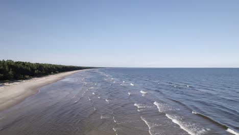 Drone-pullback-as-long-parallel-lines-of-waves-crash-on-sandy-flats-of-Baltic-coastline