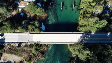 Lonely-car-driving-on-small-bridge-over-clean-river-in-Argentina,-aerial-top-down-view