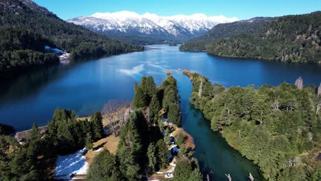 Snowy-mountains-above-blue-lake-water-in-Argentina,-aerial-view
