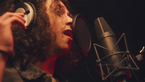 Close-Up-Shot-of-Male-Singer-Singing-Lyrical-Composition-Into-Microphone-in-Soundproof-Room