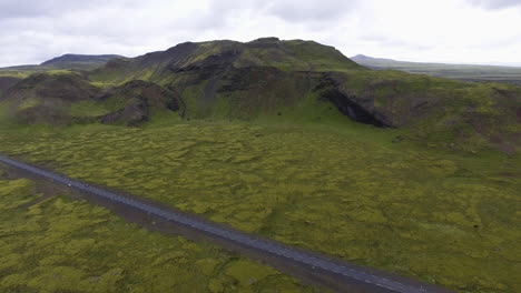 Vista-Aérea-De-La-Carretera-A-Través-Del-Campo-De-Lava-Cubierto-De-Musgo-En-Islandia.