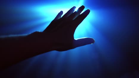 Hand-reaching-out-to-cover-shinning-spot-light