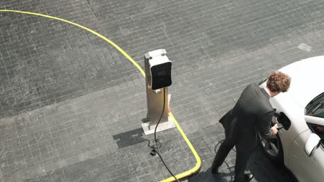 Progressive-businessman-plugs-charger-plug-from-charging-station-to-his-EV.