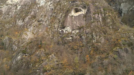 Approaching-drone-shot-of-a-rock-face-in-the-village-of-Cavergno,-in-the-district-of-Vallemaggia,-canton-of-Ticino,-in-Switzerland