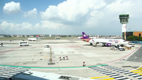 Wide-view-of-an-airport-tarmac-with-planes-and-control-tower