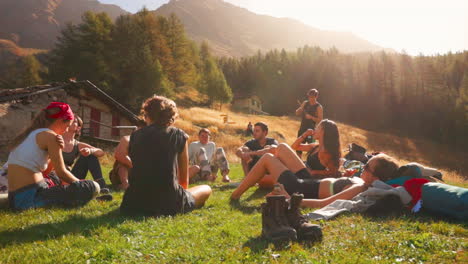Gruppe-Von-Touristenfreunden,-Die-Im-Sommer-Auf-Gras-In-Der-Italienischen-Alpenregion-Courmayeur-Mit-Malerischer-Umgebung-Sitzen