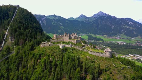 Panoramic-aerial-view-of-castle-Ehrenberg-at-foothills-of-alps,-Highline-179-pedestrian-suspension-bridge,-and-mountains-in-the-background,-Reutte,-Austria