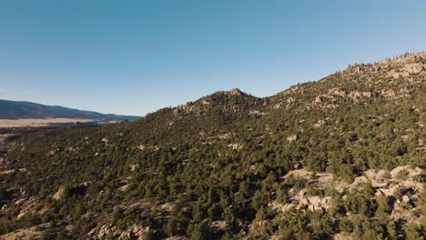 Drone-flying-over-Midland-Hill-in-Colorado-with-mountains-in-the-background-and-trees-in-foreground