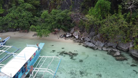 Crew-of-island-hopping-tour-boat-serving-lunch-for-tourists-on-tropical-beach,-Coron