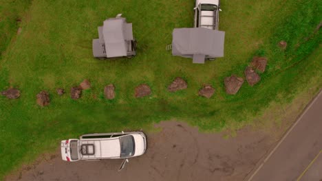 Bird-eye-aerial-over-camping-vans-and-built-up-tents-on-it,-outdoor-car-exploration,-vacation-and-camping-concept
