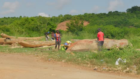 Grupo-De-Carpinteros-Africanos-Trabajando-En-Canoas-De-Madera-Con-Motosierras