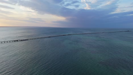 Drone-flying-over-Busselton-Jetty-at-sunset-as-train-goes-along-the-timber-pier