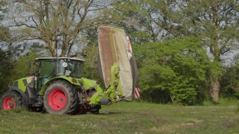 Claas-tractor-with-a-mower-on-the-field,-drive-away,-side-view