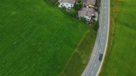 Aerial-view-of-the-car-driving-on-empty-road-in-Swiss-village,-Sorenberg,-Switzerland