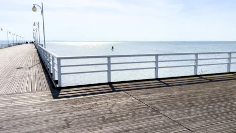 Long-wooden-pier-extending-into-the-calm-sea-under-a-clear-sky
