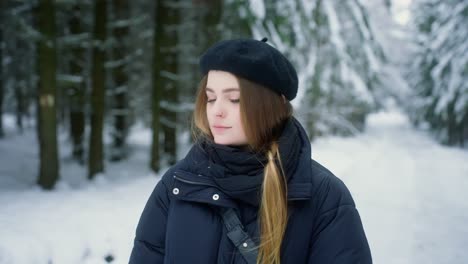 Schönes-Mädchen-Mit-Baskenmütze,-Langen-Haaren-Und-Winterkleidung-In-Einem-Schneebedeckten-Wald