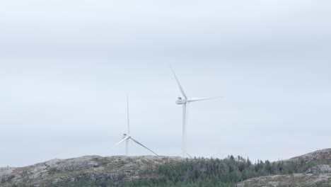 Hildremsvatnet,-Trondelag-County,-Norway---A-Windmill-Positioned-Atop-a-Hill,-Enveloped-by-a-Surrounding-of-Coniferous-Trees---Wide-Shot