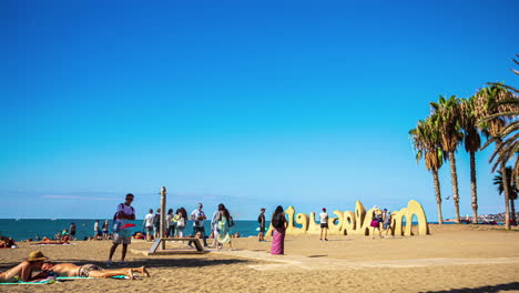 Time-lapse-people-moving-on-beach-close-to-Malaga-sign-in-Spain,-Mediterranean-Sea
