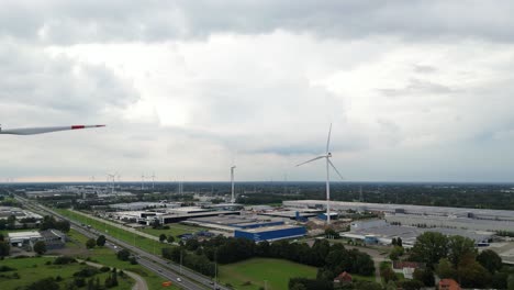Wind-turbines-generate-energy-for-industrial-part-of-city,-aerial-view