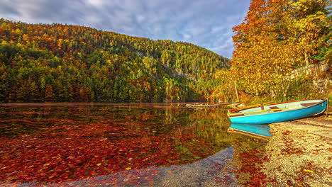 Timelapse-of-a-boat-at-a-lake,-colorful-autumn-foliage-in-the-alps-of-Austria