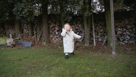 Toddler-playing-and-exploring-beautiful-big-garden-in-winter-time,-wearing-winter-clothing