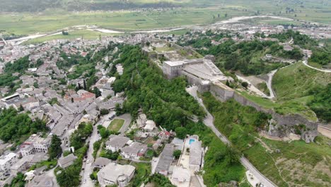 Drone-view-in-Albania-flying-in-Gjirokaster-town-over-a-medieval-castle-on-high-ground-lateral-and-top-view