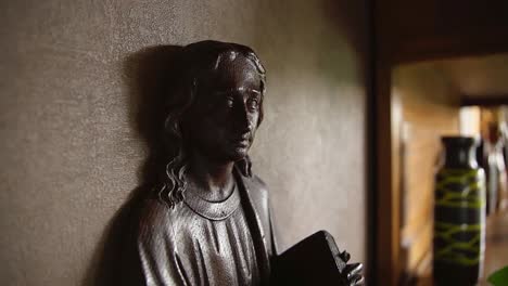 Close-up-view-of-small-indoor-statue-of-Jesus-Christ-holding-the-bible-in-relgious-home