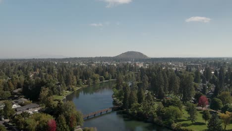 Aerial-shot-over-the-Deschutes-River-winding-through-in-Bend,-Oregon-with-a-view-of-Pilot-Butte-in-the-distance