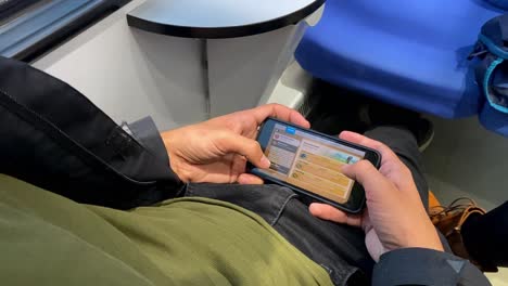 While-traveling-by-train-in-Bari,-Italy,-a-man-enjoys-playing-a-video-game-on-his-mobile-device