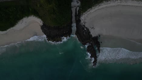 Top-down-of-coastal-waves-and-rocky-cliffs-in-Lombok,-Indonesia-just-after-sunset
