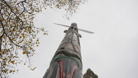 A-low-angle-orbiting-shot,-moving-from-right-to-left,-showcasing-a-Totem-Pole-against-a-backdrop-of-rain-and-overcast-skies