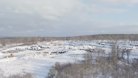 Snow-Covered-Outdoor-Industrial-Materials-Supply-Yard-in-the-Winter,-Aerial-Flyover