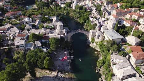 Turistas-En-El-Famoso-Puente-Stari-Most-En-La-Ciudad-Balcánica-De-Mostar,-Inclinación-Aérea-Hacia-Arriba