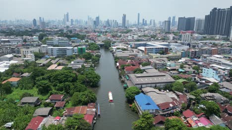 City-and-river-scenes-while-following-a-boat-in-Bangkok,-Thailand