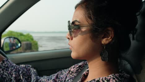 Close-up-shot-of-a-female-driver-with-the-stopped-car-looking-away-wearing-sunglasses