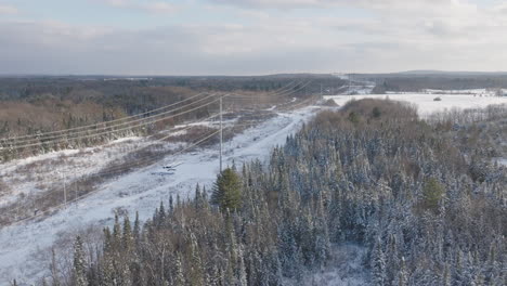 Transmission-Lines-in-a-Snowy-Rural-Winter-Forest-Landscape,-Aerial