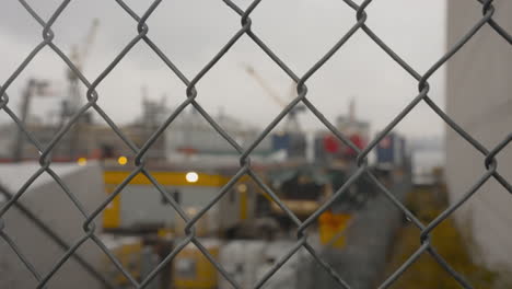 A-right-to-left-dolly-captures-a-sharply-focused-chain-link-fence,-with-the-Vancouver-Seaspan-drydock-blurred-in-the-background