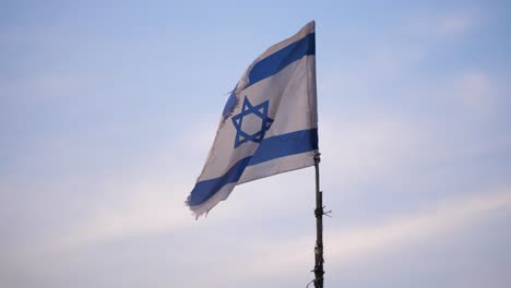 Israeli-blue-and-white-flag-raised-on-a-makeshift-flagpole-blows-in-the-breeze